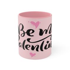 a pink coffee mug with the words be my valentine written on it and hearts in black ink