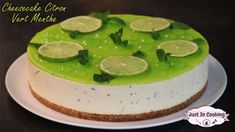 a cheesecake with limes and mint on top sitting on a white platter