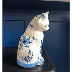 a white and blue cat figurine sitting on top of a black countertop