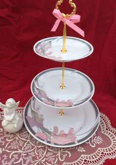 three tiered cake stand with pink bows on top and white plates stacked on each other