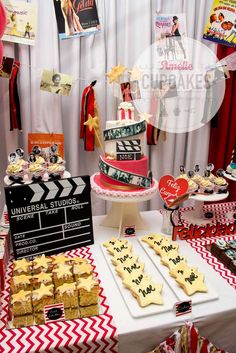 a table topped with lots of cakes and desserts next to a movie clapper