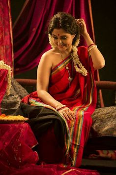 a woman in a red sari sitting on a bed