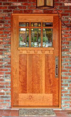 a wooden door with glass on the side of a brick wall and stone steps leading up to it