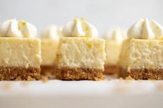 four pieces of cheesecake with whipped cream on top are lined up in a row