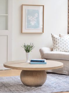 a living room with a couch, coffee table and books on the floor in front of it