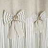 three bow tie curtains hanging on the side of a window with white and beige striped drapes