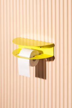 a yellow shelf with two rolls of toilet paper hanging from it's side and a roll of tissue on top