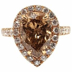 an engagement ring with a pear shaped brown diamond surrounded by white and yellow diamonds in the center