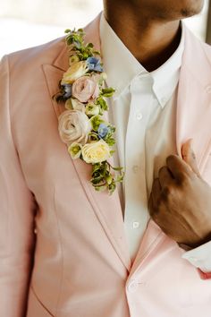 a man in a pink suit with flowers on his lapel