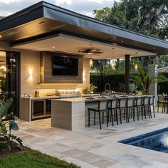 an outdoor kitchen and dining area next to a pool