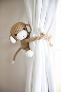 a stuffed monkey hanging from the side of a curtain