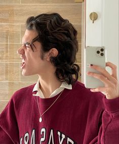 a man with long hair and glasses taking a selfie in front of a mirror