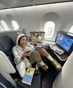 a woman sitting on an airplane seat looking at her cell phone