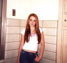 a woman standing in front of a tiled wall with her hands on her hips and looking at the camera