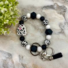 a bracelet with black and white beads on top of a marble table next to a potted plant