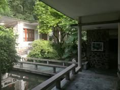 a house with trees and water in the front yard, surrounded by greenery on both sides