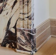 the corner of a room with wood flooring and marble columns on it's sides