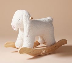 a white stuffed dog sitting on top of a wooden rocking toy