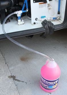 a pink bottle with a hose attached to it next to a car's engine