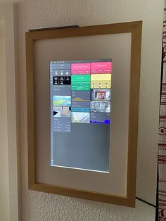 a computer monitor mounted to the side of a wall next to a window with pictures on it