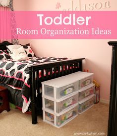 a toddler's room with pink walls, black and white bedding and storage bins