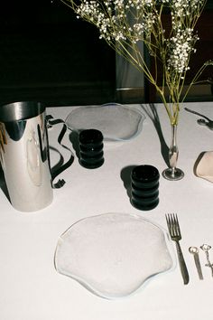 the table is set with plates, silverware and flowers in a vase on it