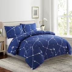 a blue comforter set with white stars on it in a room next to a window