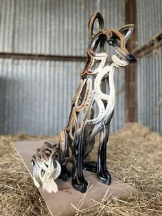 a metal dog sculpture sitting on top of hay