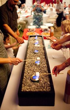 a group of people standing around a table with candles on it