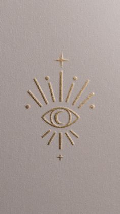 an eye and cross drawn in sand on the side of a white paper with gold foil