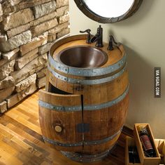 a wooden barrel sink sitting on top of a hard wood floor next to a round mirror