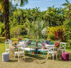 a table and chairs in the middle of a lawn with palm trees behind it,