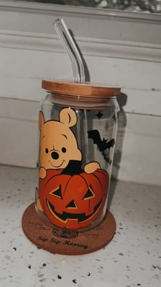 a winnie the pooh pumpkin jar with a straw in it sitting on a counter