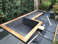 an outdoor hot tub in the middle of a garden with gravel and plants around it