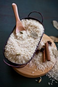 a wooden spoon sitting in a bowl filled with white rice and cinnamons on top of a table