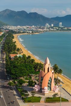 an aerial view of the beach and ocean with mountains in the background, including palm trees