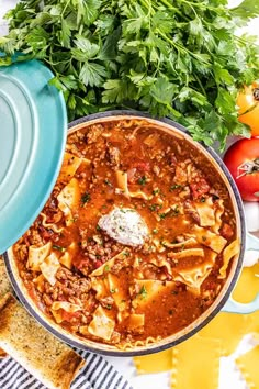 a bowl of pasta soup with bread and parsley on the side next to it