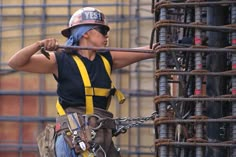 a man in safety gear is holding a pole and working on a construction site with lots of pipes