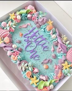 a birthday cake decorated with seashells and seahorses is in a box