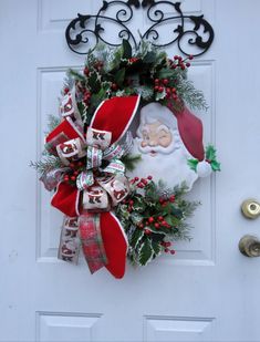 a christmas wreath hanging on the front door with santa clause and holly berry garland around it