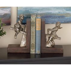 two bookends with metal figurines sitting on top of each other in front of a painting