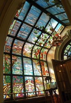 an ornate stained glass window in a church with chandelier hanging from the ceiling