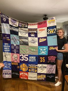 two women standing next to a large quilt covered in t - shirts and other items