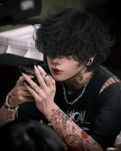 a woman with black hair and piercings holding a cell phone in her hands while looking at the screen