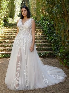 a woman standing in front of some bushes wearing a white dress with sheer lace on it