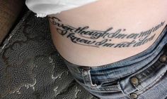 a woman with a tattoo on her stomach that reads, the words are written in cursive writing