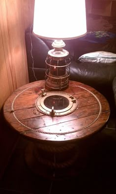 a wooden table with a lamp on top of it next to a black leather couch