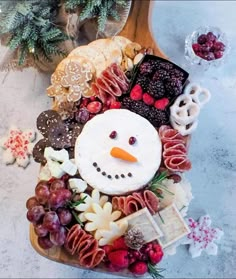 a snowman made out of food on top of a wooden board next to christmas decorations