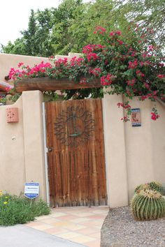 a wooden door surrounded by pink flowers next to a cactus and succulent plant