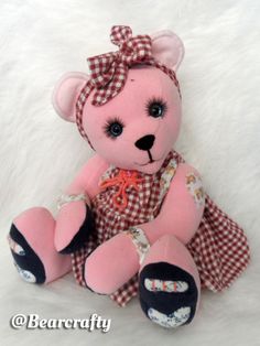 a pink teddy bear with a red and white checkered dress on it's chest